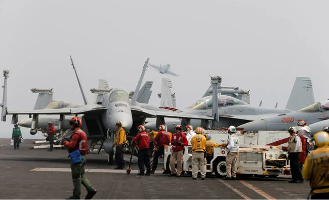 Flight-deck crew members of the US aircraft carrier USS Nimitz are seen as planes take of behind them in the Arabian Gulf on August 15, 2017. (REUTERS/Hamad I Mohammed)