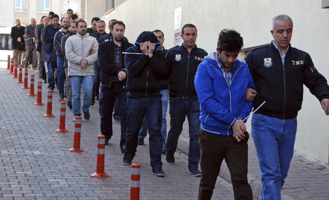 In this April 26, 2017 photo, Turkish police officers escort people arrested in Kayseri because of suspected links to US-based cleric Fethullah Gulen. On Friday, Turkish authorities dismissed over 900 public sector officials in the latest wave of the purge that followed last year’s failed coup. (Olay Duzgun/DHA-Depo Photos via AP)