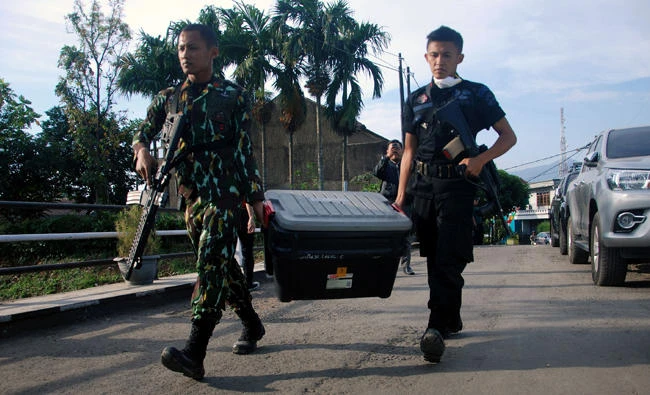 Police carry a box of evidence during a terror raid at the Jajaway village in Bandung on August 15, 2017. Five suspected Daesh sympathizers have been arrested in the raid and authorities also confiscated a chemical bomb. (AFP / Timur Matahari)