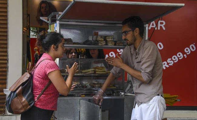 Egyptian immigrant Mohamed Ali Abdelmoatty Kenawy, who was attacked three weeks ago by four men screaming "Go back to your country!", attends to a customer at his food stand in the Copacabana neighborhood in Rio de Janeiro on August 24, 2017. (AFP / Apu Gomes)