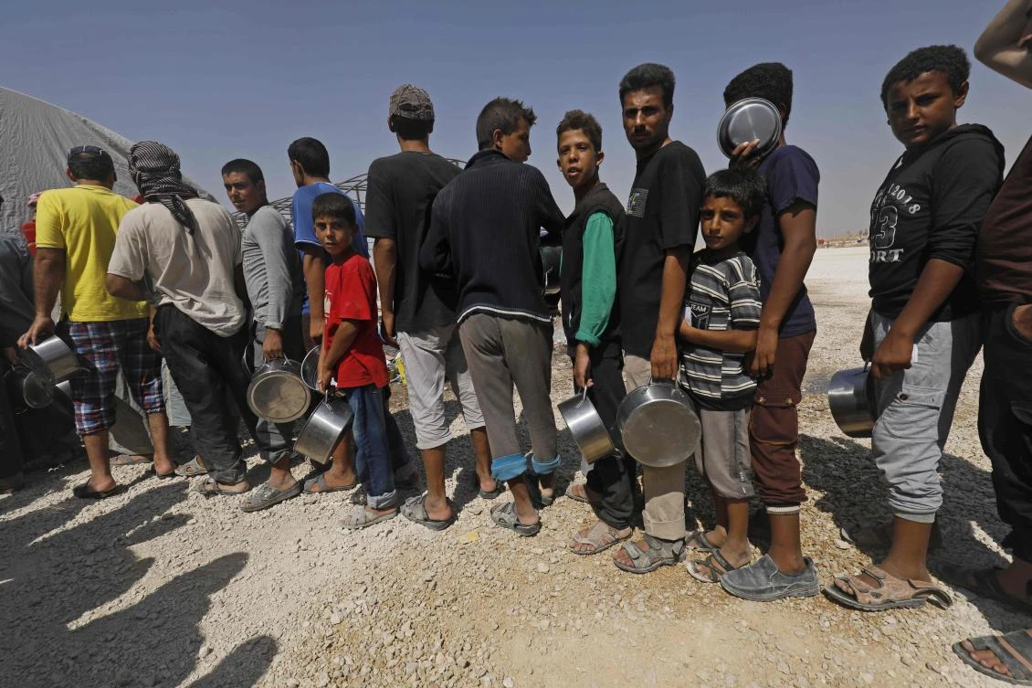 Displaced Syrians queue up to receive food at the Al-Mabrouka camp in the village of Ras Al-Ain on the Syria-Turkey border. (AFP)