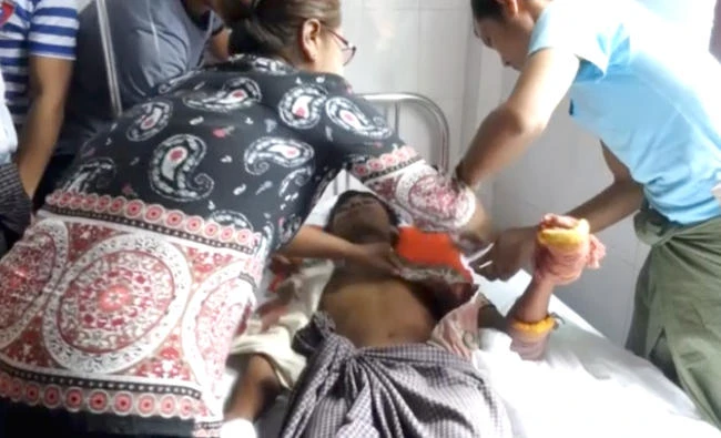 In this photo made from video, a man lying on a bed with a bandaged hand is cared for in a hospital in Buthidaung township, Myanmar, on Friday. (AP)