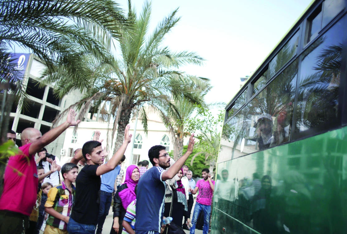 Palestinians wave to say goodbye to their relatives on a bus before leaving for the annual Hajj pilgrimage to the holy city of Makkah, in Gaza City. (AP)