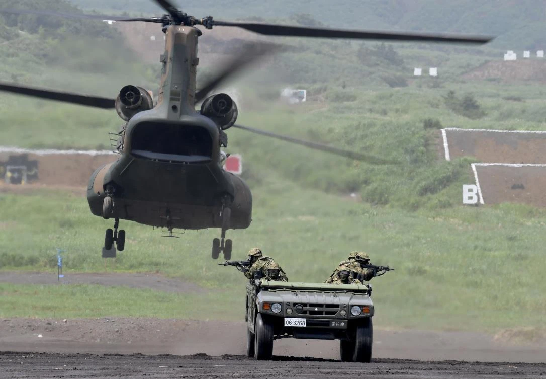 A Japan Ground Self-Defense Forces vehicle moves toward a hoovering CH-47 helicopter during an annual live-fire exercise at the Higashi-Fuji firing range in Gotemba, at the foot of Mount Fuji in Shizuoka prefecture on August 24, 2017. The annual drill involves some 2,400 personnel, 80 tanks and armoured vehicles and some 20 aircraft and helicopters. (AFP)