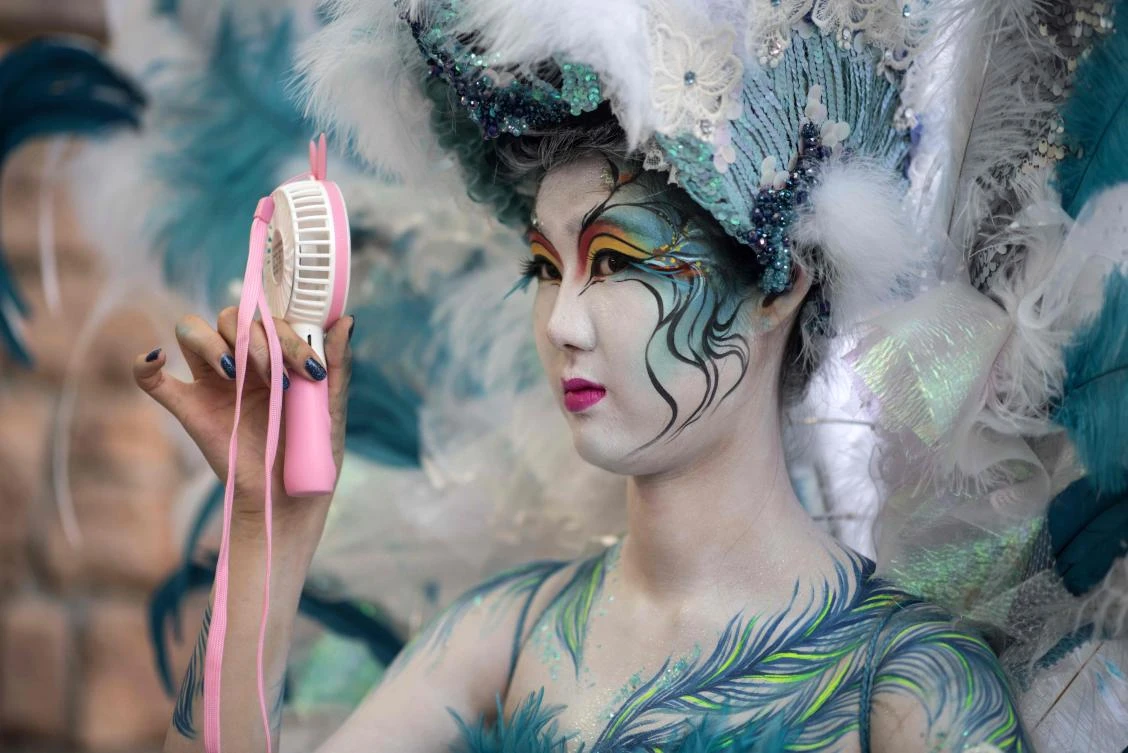 In this photo taken on August 26, 2017, a model uses a portable fan to keep cool backstage during the Daegu International Bodypainting Festival in Daegu. The bodies of dozens of female models turned into living canvases this weekend as they allowed delicate brush strokes and flamboyant illustrations to cover up their bare skin. They are part of the 2017 Daegu International Bodypainting Festival along with top artists from 10 countries that runs until August 27 in South Korea's southeastern city of Daegu. (AFP)