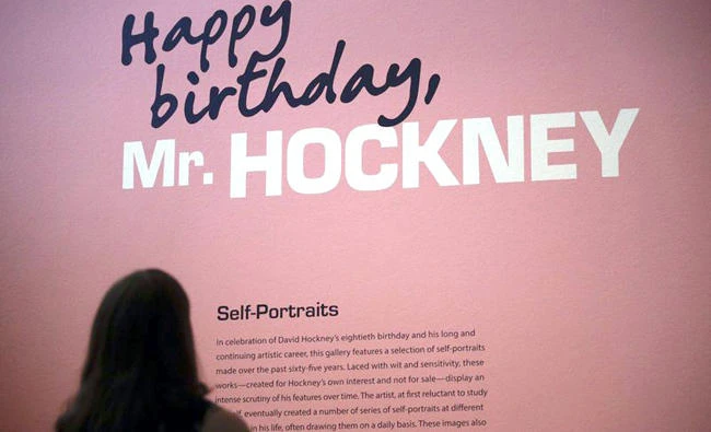 A senior communications specialist from J. Paul Getty Trust, reads a brief description of David Hockney’s self-portraits in the exhibition hall at the Getty Center in Los Angeles. (AP)