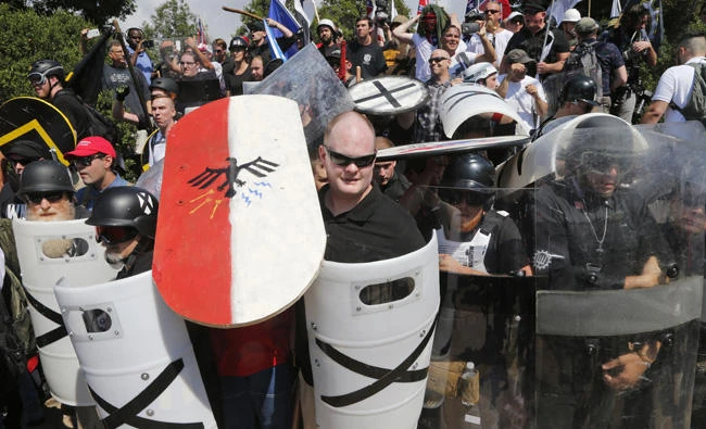 In this Aug. 12, 2017 file photo, US white nationalist demonstrators use shields as they guard the entrance to Lee Park in Charlottesville, Virginia. A company on Monday revoked the site operated by a white supremacist group following complaints that it promotes hatred and is linked to dozens of murders. (AP Photo/Steve Helber, File)