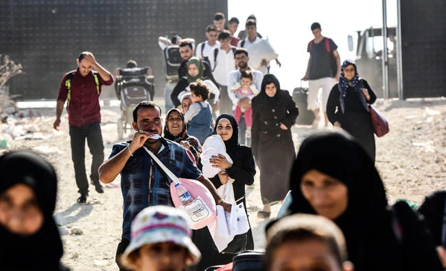 Syrian refugees arrive at the Oncupinar crossing gate, close to the town of Kilis, south central Turkey, in order to cross to Syria for the Eid al-Adha Muslim holiday on August 27, 2017. Turkish authorities allow Syrian refugees to visit their country for Eid-Al-Adha (Feast of the Sacrifice) celebrities. (AFP)