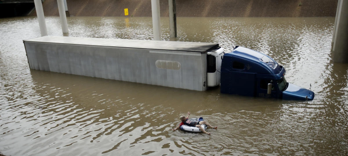 After helping the driver of the submerged truck get to safety, a man floats on the freeway flooded by Tropical Storm Harvey on Aug. 27, 2017, near downtown Houston. (AP Photo/Charlie Riedel)