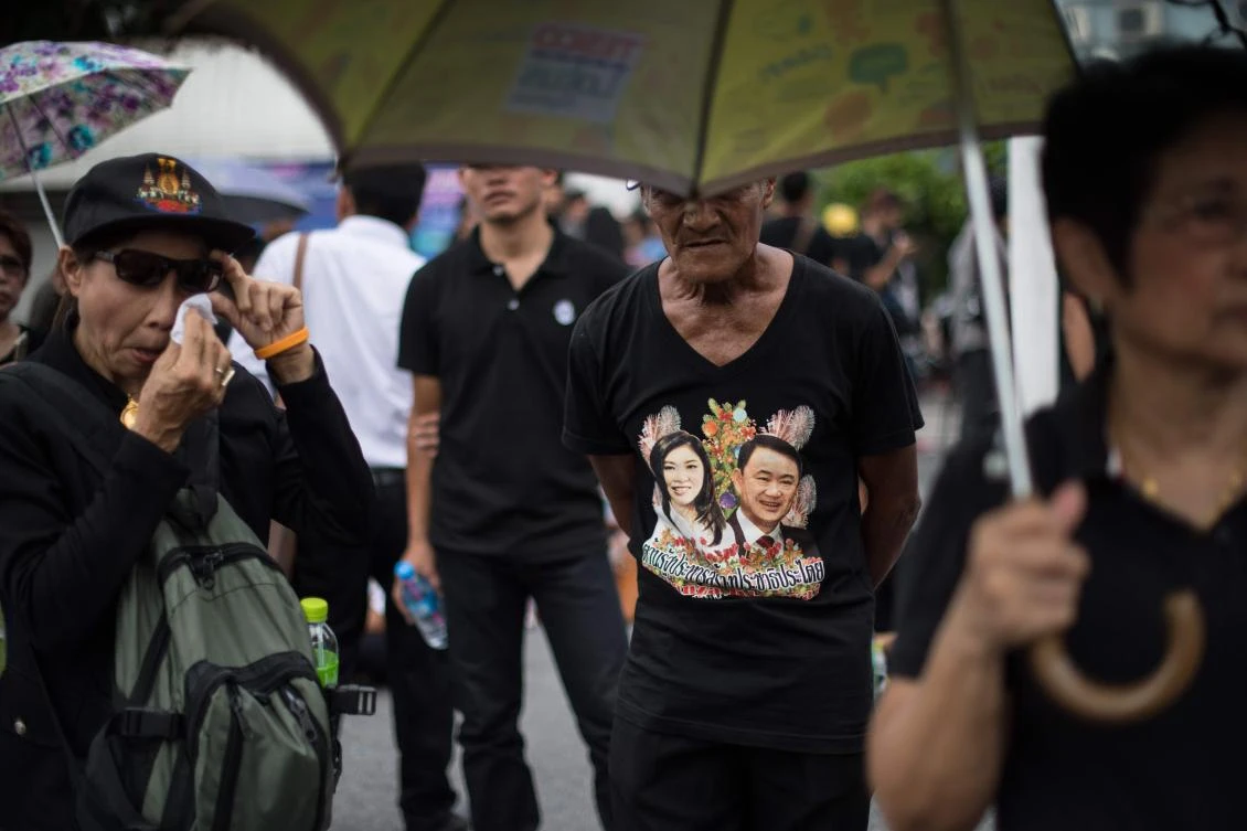 A supporter of former Thai Premier Yinluck Shinawatra, wearing a t-shirt decorated with an image of Shinawatra and her brother Thaksin, stands in front of the Supreme Court after news broke that Shinawatra would not appear in court in Bangkok on August 25, 2017. Thai ex-prime minister Yingluck Shinawatra missed a verdict in a negligence trial on August 25 that could have seen her jailed, prompting the Supreme Court to issue an arrest warrant fearing she is a flight risk, a judge said. / AFP / ROBERTO SCHMIDT