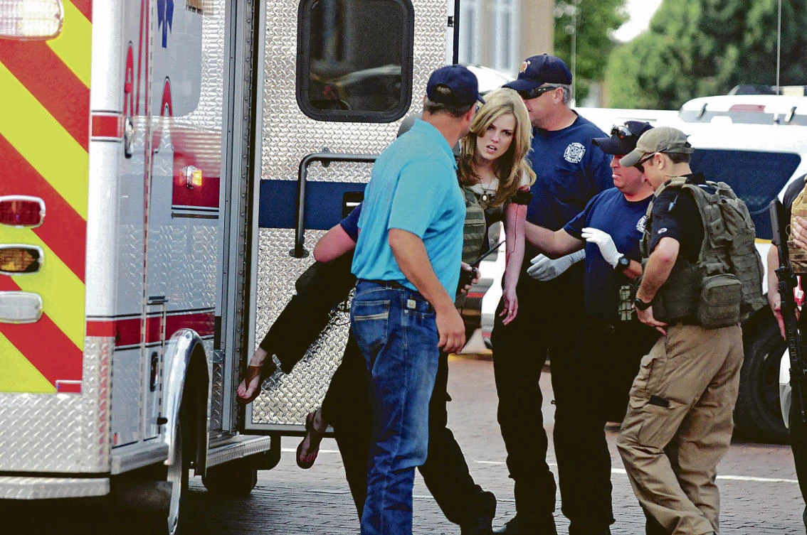 An injured woman is carried to an ambulance in Clovis, N.M., Monday, Aug. 28, 2017, as authorities respond to reports of a shooting inside a public library. A city official says police have taken a person into custody who they believe is responsible for a shooting at the library. (Tony Bullocks/The Eastern New Mexico News via AP)