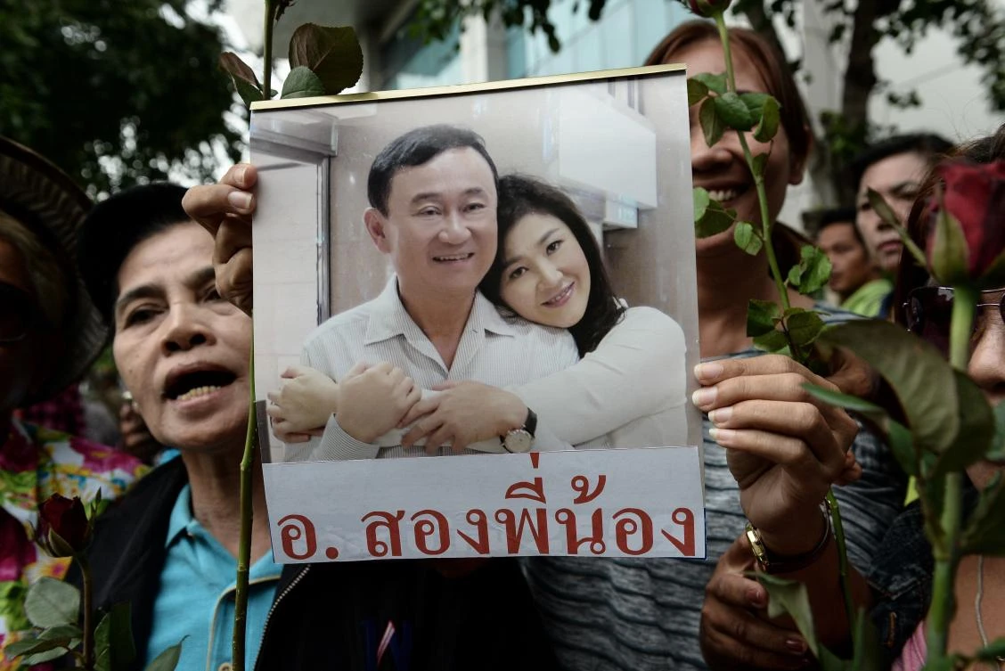 (FILES) This file photo taken on August 5, 2017 shows a woman holding an image of former Thai prime minister Yingluck Shinawatra with her brother, ex prime minister Thaksin Shinawatra, before Yingluck arrives at the Supreme Court in Bangkok. Fugitive former Thai prime minister Thaksin Shinawatra hit out at "tyranny" on August 30, 2017 via a cryptic tweet quoting a French enlightenment thinker in his first comments since his sister, Yingluck Shinawatra, fled overseas. Yingluck, who like her brother was also booted from office by Thailand's military, dramatically disappeared days before a court was about to deliver judgement in a criminal negligence trial. (AFP)
