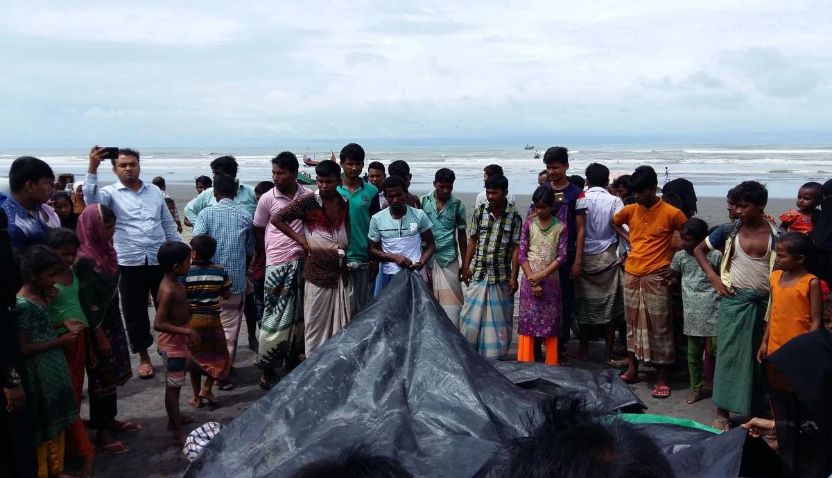 Bangladeshi onlookers watch as a man covers the bodies of the drowned Rohingya women and children, on August 31, 2017. (AFP)