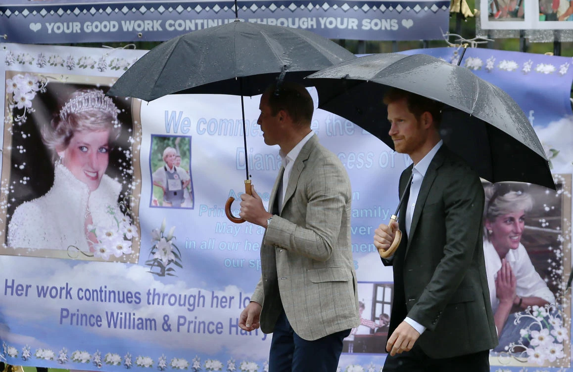 TOPSHOT - Britain's Prince William, Duke of Cambridge (L) and Britain's Prince Harry look at tributes left by members of the public at one of the entrances of Kensington Palace to mark the coming 20th anniversary of the death of Diana, Princess of Wales, in London on August 30, 2017. Princes William and Harry prepared to pay tribute to their late mother Princess Diana on Wednesday for the 20th anniversary of her death as wellwishers left candles and flowers outside the gates of her former London residence. The Princes visited the Sunken Garden in the grounds of Kensington Palace, which this year has been transformed into a White Garden, dedicated to their late mother, Britain's Diana, Princess of Wales. (AFP)