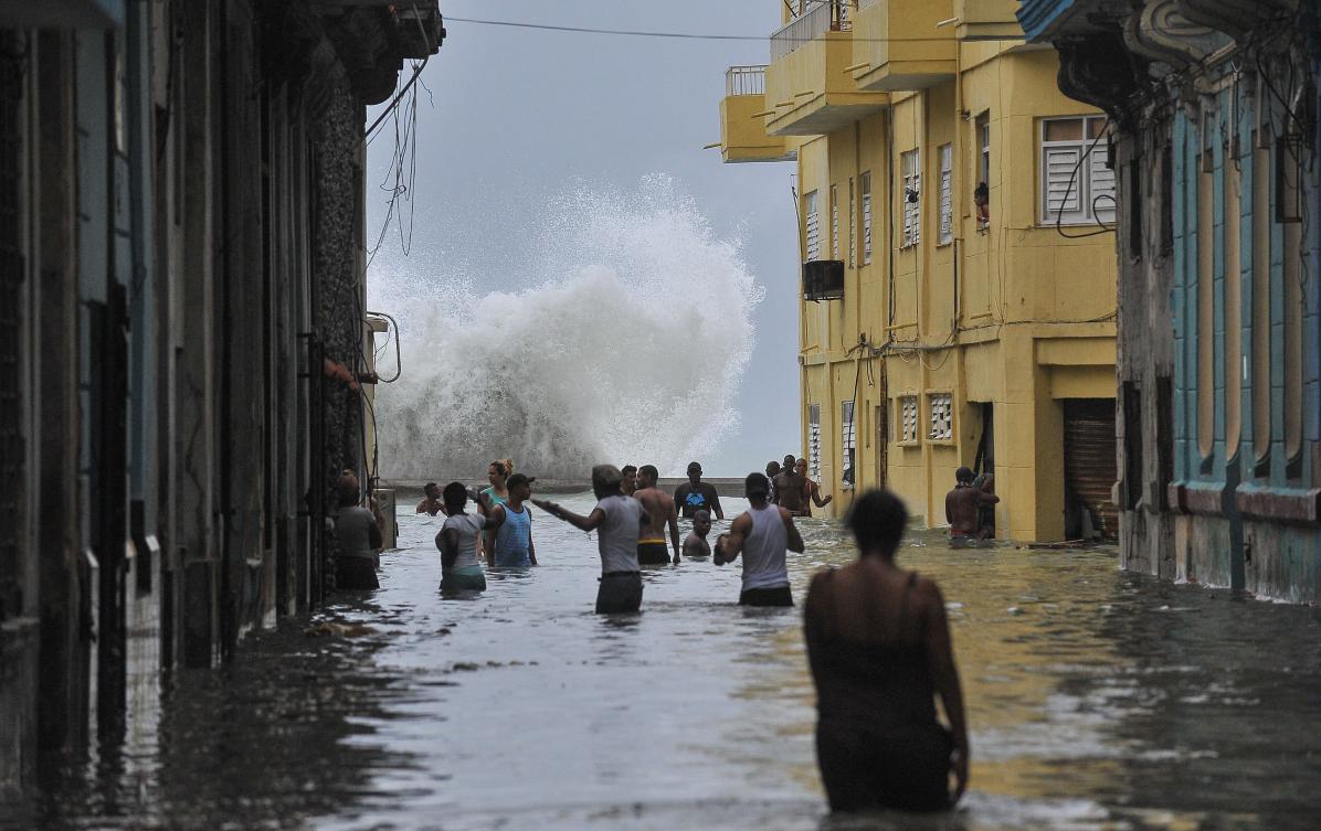 TOPSHOT - Cubans wade through a flooded street in Havana, on September 10, 2017. Deadly Hurricane Irma battered central Cuba on Saturday, knocking down power lines, uprooting trees and ripping the roofs off homes as it headed towards Florida. Authorities said they had evacuated more than a million people as a precaution, including about 4,000 in the capital. / AFP / YAMIL LAGE