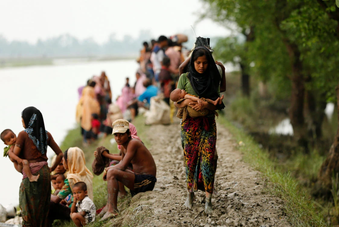 A Rohingya refugee woman with her child walks on the muddy path after crossing the Bangladesh-Myanmar border in Teknaf, Bangladesh, September 7, 2017. REUTERS/Mohammad Ponir Hossain