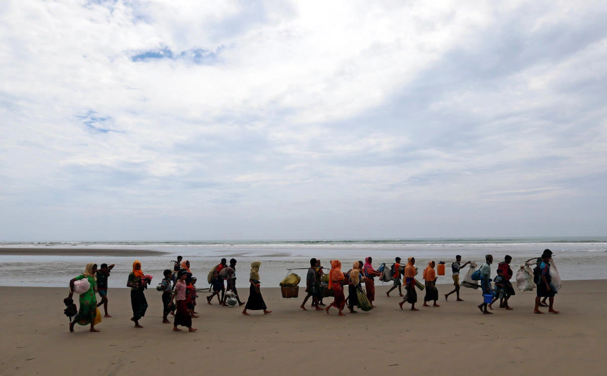 Rohingya refugees walk on the shore with their belongings after crossing the Bangladesh-Myanmar border by boat through the Bay of Bengal in Teknaf, Bangladesh, September 7, 2017. REUTERS/Danish Siddiqui