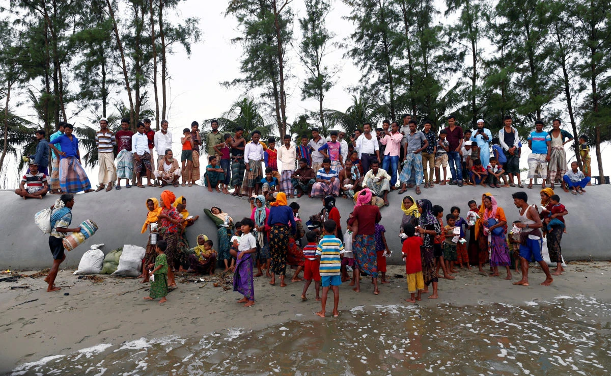 Local residents watch as Rohingya refugees arrive on the shore after crossing the Bangladesh-Myanmar border by boat through the Bay of Bengal in Teknaf, Bangladesh, September 7, 2017. REUTERS/Danish Siddiqui