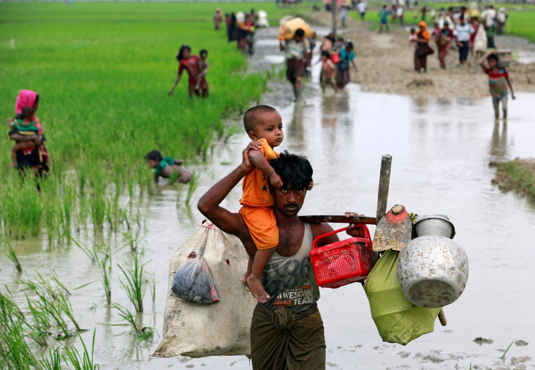 A Rohingya refugee carries a child through a paddy field after crossing the Bangladesh-Myanmar border, in Teknaf, Bangladesh, September 6, 2017. REUTERS/Danish Siddiqui TPX IMAGES OF THE DAY