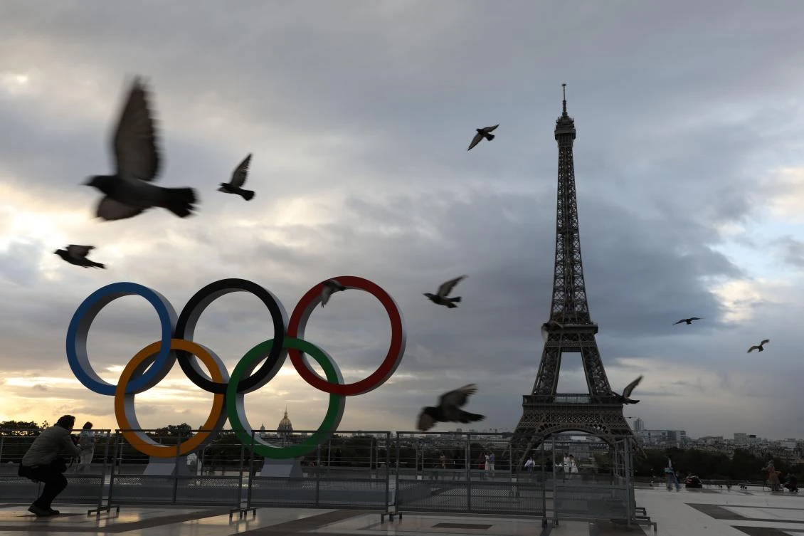 pigeons fly past the Olympic rings installed on the Esplanade du Trocadero near the Eiffel tower following the Paris' nomination as host for the 2024 Olympics, are pictured on September 14, 2017 in Paris. / AFP / LUDOVIC MARIN