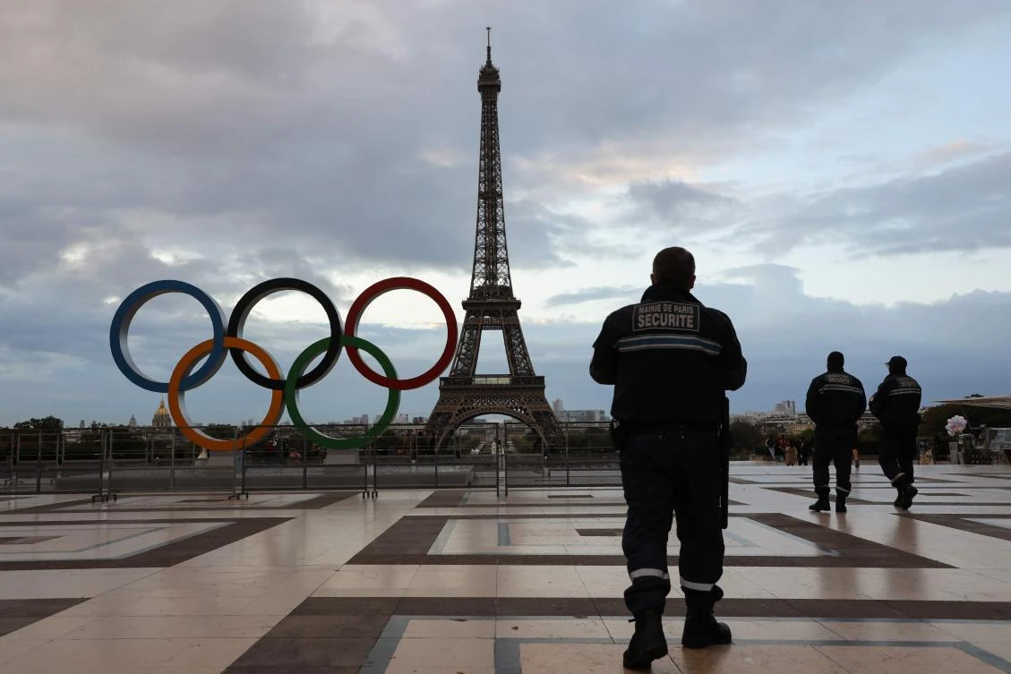 Security guards patrol at sunrise by the Olympic rings installed on the Esplanade du Trocadero near the Eiffel tower following the Paris' nomination as host for the 2024 Olympics, on September 14, 2017 in Paris. / AFP / LUDOVIC MARIN