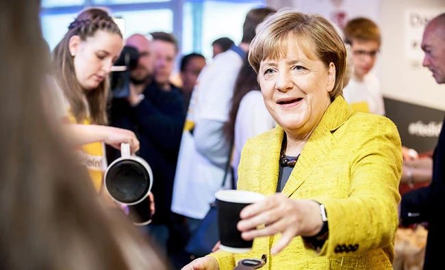 German chancellor Angela Merkel drinks a cup of coffee with election campaign workers in Berlin, on Saturday, ahead of Germany's election on Sunday. (AP)