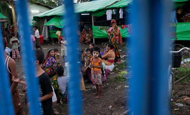 This photograph taken on September 21, 2017 shows a Hindu girl wearing traditional thanaka make-up looking out through the gate of the camp for displaced Hindus in the Sri Sri Moha Dev Bari Hindu Temple in Sittwe, in Myanmar's Rakhine state. (AFP / Aidan Jones)