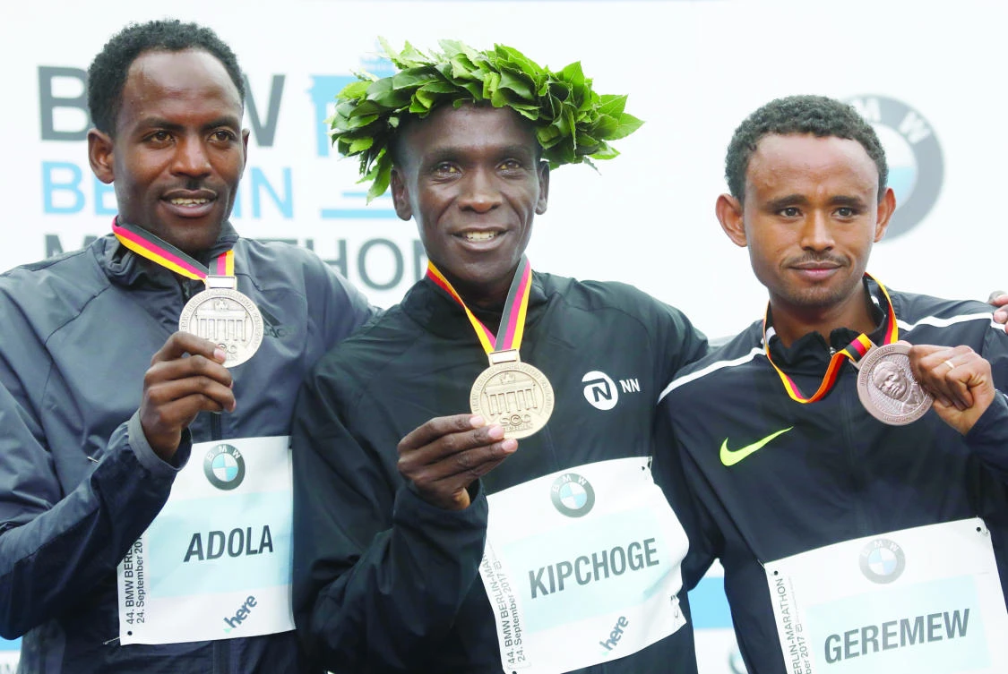 Winner Eliud Kipchoge of Kenya, center, second placed Ethiopian Guye Adola, left, and third placed Ethiopian Mosinet Geremew celebrate on the podium after the Berlin Marathon on Sunday in Berlin. (AFP)
