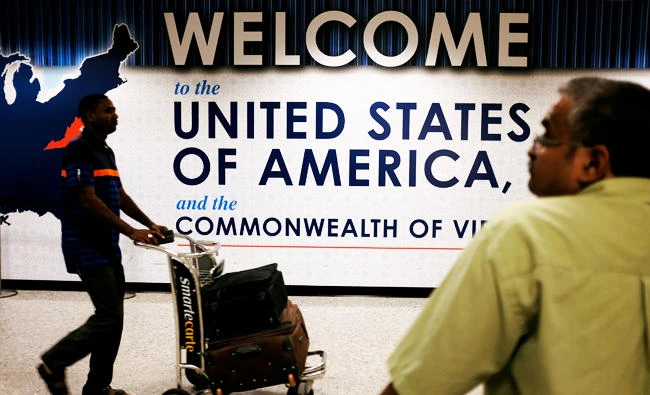An international passenger (L) arrives at Dulles International Airport as a man (R) waits for loved ones to arrive in Dulles, Virginia, U.S. on Monday. (REUTERS)