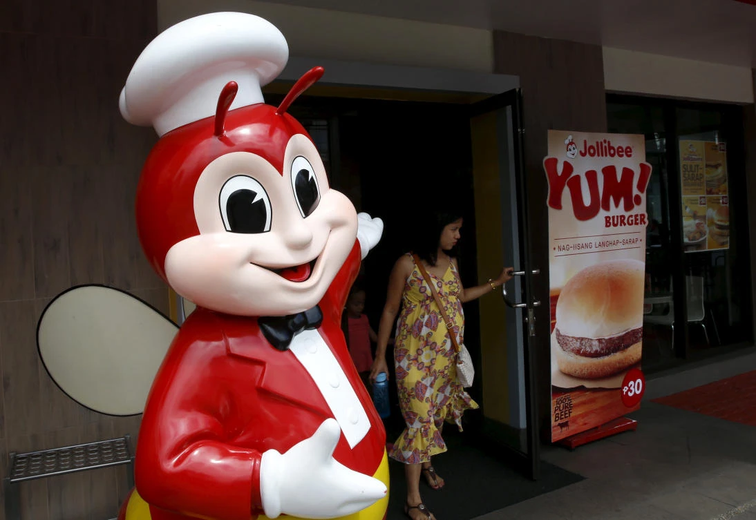 A customer walks past a Jollibee mascot at the entrance of a Jollibee franchise in Paranaque, Metro Manila. (Reuters)