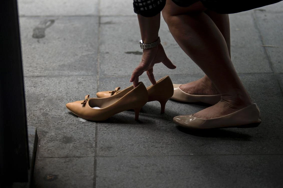 An office worker changes her footwear from high-heeled to flat shoes outside her office in Makati, Manila's financial district, on September 25, 2017. The Philippines has banned companies from compelling women to wear high heels to work under a government order hailed by labour groups on September 25 as a victory against sexism and torture. (AFP)