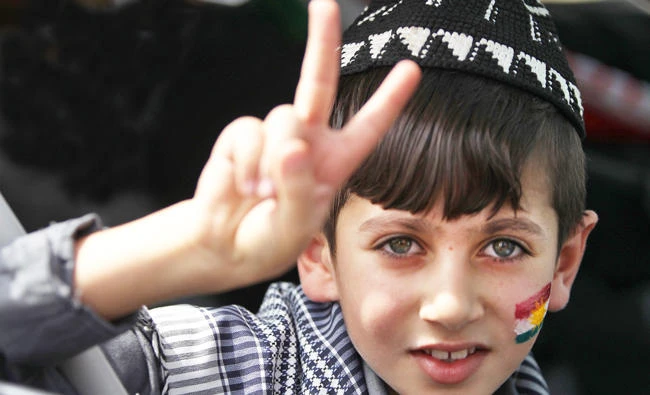 An Iraqi Kurdish boy with the Kurdish flag painted on his cheek flashes the victory sign in Kirkuk. (AFP)