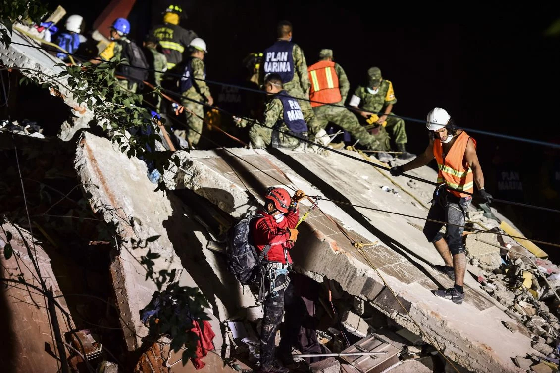 Rescuers, firefighters, policemen, soldiers and volunteers remove rubble and debris from a flattened building in search of survivors after a powerful quake in Mexico City on September 19, 2017. (AFP)