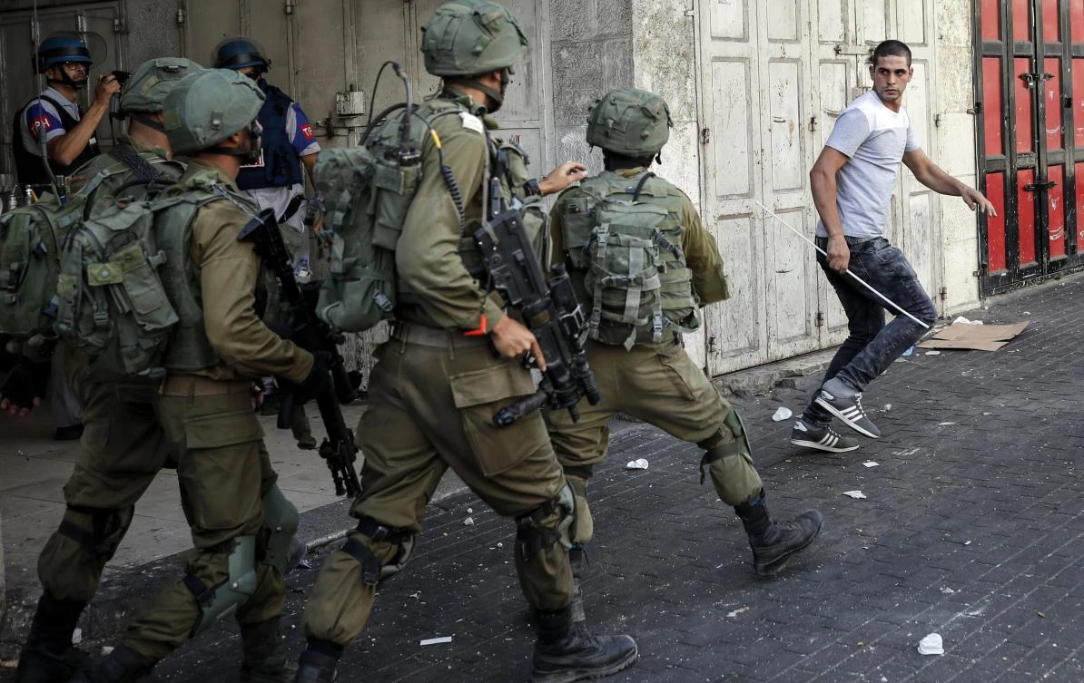 A Palestinian man runs during a demonstration as Israeli soldiers try to catch him, in the West Bank city of Hebron on September 15, 2017. (AFP)