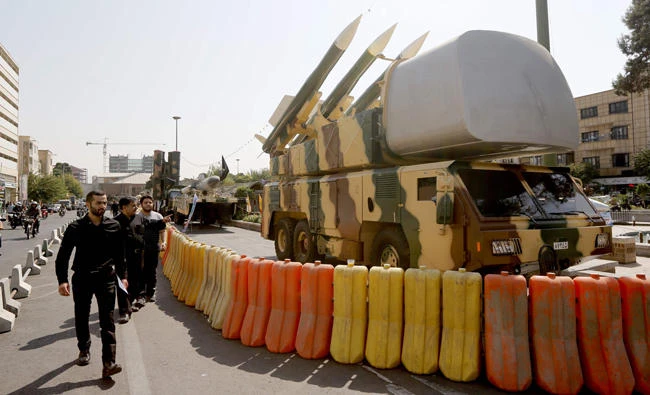 People walk past missile defense systems displayed on Baharestan Square in Tehran on September 25, 2017, on the occasion of the annual defense week which marks the anniversary of the 1980s Iran-Iraq war. (AFP / ATTA KENARE)