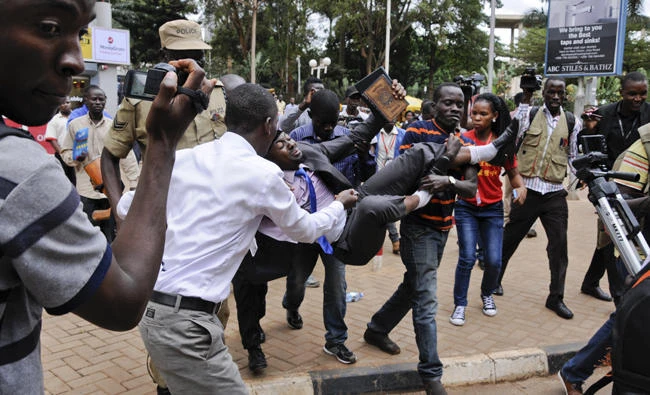 An activist opposed to the extension of presidential age limits is arrested and carried off by uniformed and plainclothes police near the Parliament building in Kampala, Uganda, on Sept. 21, 2017. Ugandan police on Thursday fired tear gas to disperse protesters and arrested dozens of people opposed to plans to introduce legislation that could allow the longtime president Yoweri Museveni to extend his rule. (AP Photo/Ronald Kabuubi)