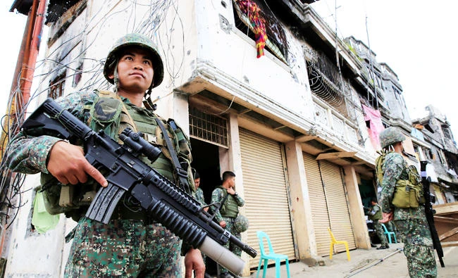 Government soldiers stand guard in front of damaged building and houses in Sultan Omar Dianalan boulevard at Mapandi district in Marawi city, southern Philippines, in this September 13, 2017 photo. (REUTERS)
