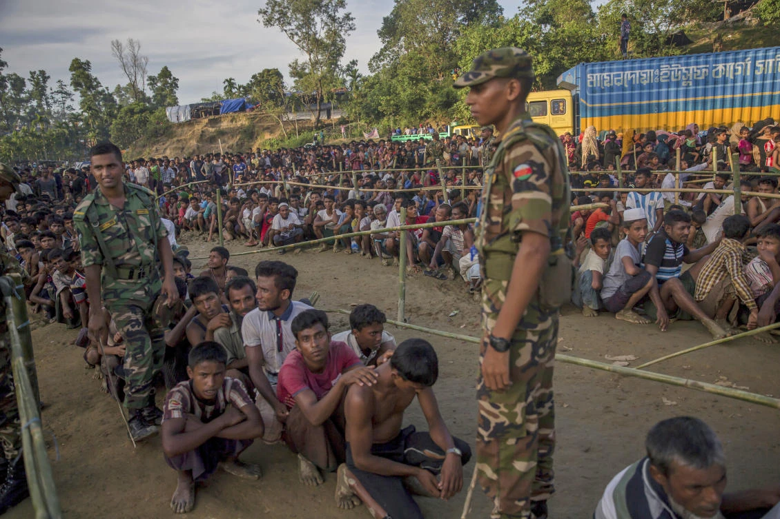 Bangladesh army men stand guard as Rohingya Muslim men, who crossed over from Myanmar into Bangladesh, wait to receive aid during a distribution near Balukhali refugee camp, Bangladesh, Monday, September 25, 2017. (File photo by AP)