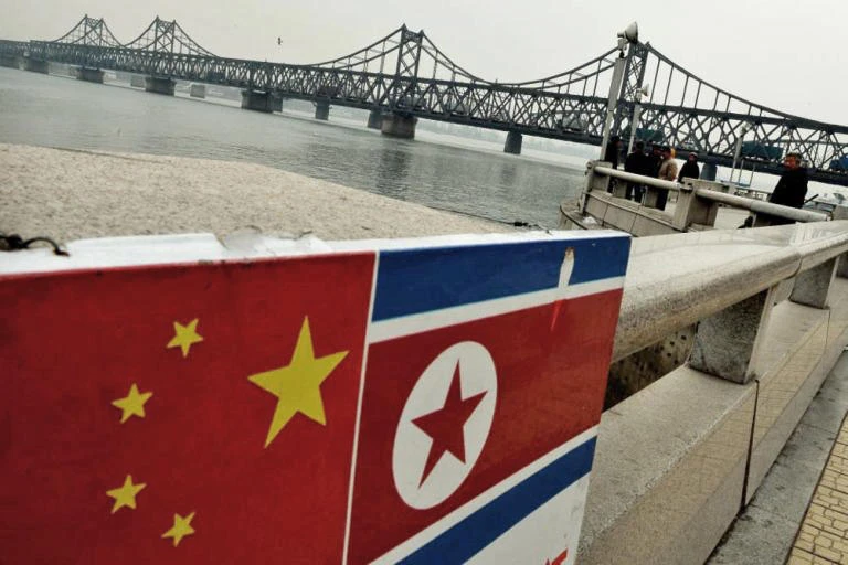 The Chinese and North Korean flags attached to a railing as trucks carrying Chinese-made goods cross into North Korea on the Sino-Korean Friendship Bridge at the Chinese border town of Dandong on December 18, 2013 (File photo by AFP)