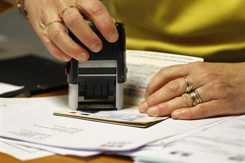 An employee validates an extension visa on a foreign student’s passport at a foreign visas office in Paris on November 18, 2011. (File photo by Reuters)