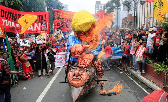 In this September 15, 2017 photo, protesters burn effigies of US President Donald Trump and Philippine President Rodrigo Duterte in front of the US embassy in Manila to express their outrage allegedly increasing US intervention in the ongoing war in Marawi city, southern Philippines. Duterte on Thursday voiced rare praise for the US, calling it an important security ally, a turnaround from his previous adversarial pronouncements. (REUTERS/Romeo Ranoco)