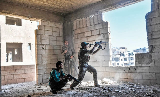 Members of the Syrian Democratic Forces fire their arms during a battle against Daesh to retake the central hospital of Raqqa on the western frontline of the city on Thursday. (AFP)