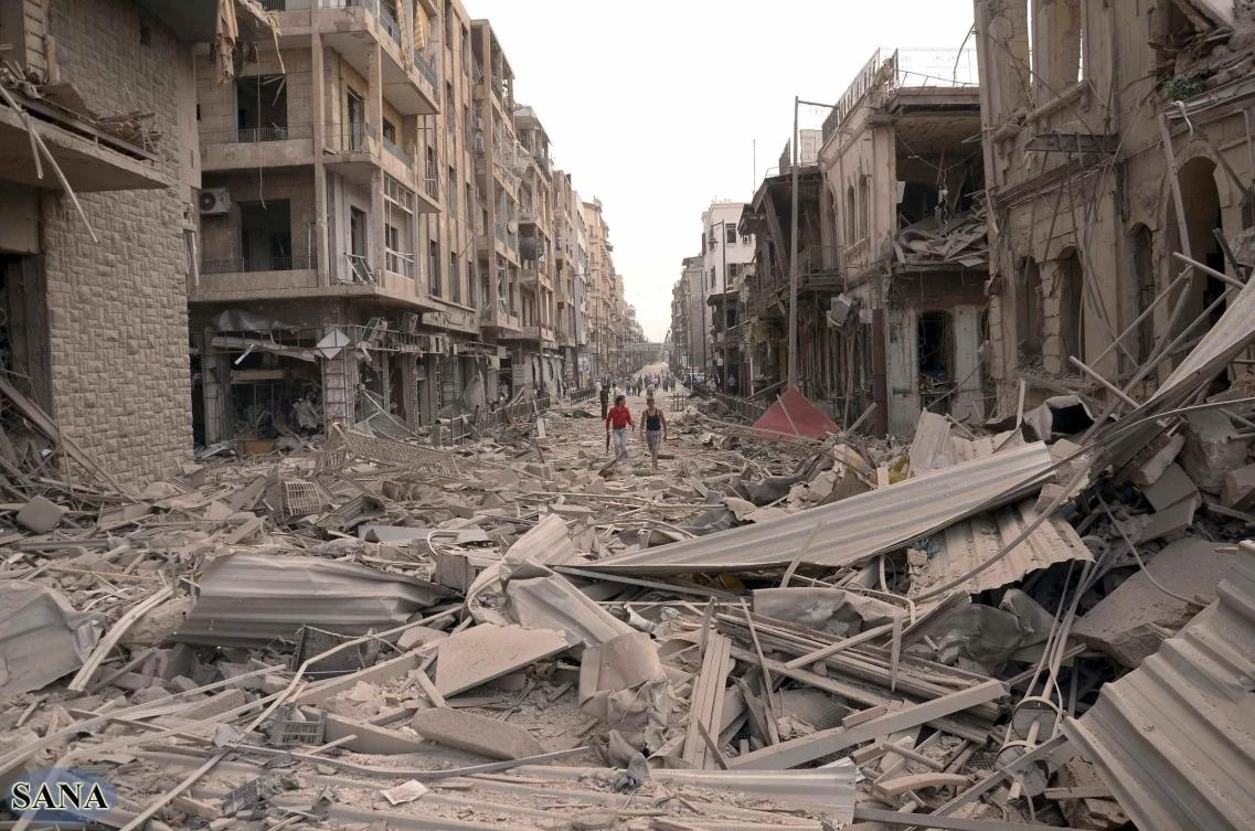 Men walk on a road amid wreckage,after three blasts ripped through Aleppo’s main Saadallah Al-Jabari Square on Wednesday. (Reuters)