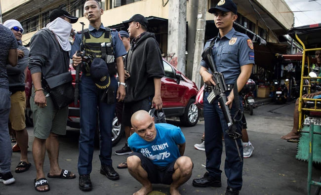 An alleged drug dealer is captured by policemen after a drug buy-bust operation on a slum area in Manila on September 28, 2017. Nearly half of Filipinos believe police are killing innocent people in waging President Rodrigo Duterte's anti-drugs war, according to survey results released Wednesday. (AFP / NOEL CELIS)