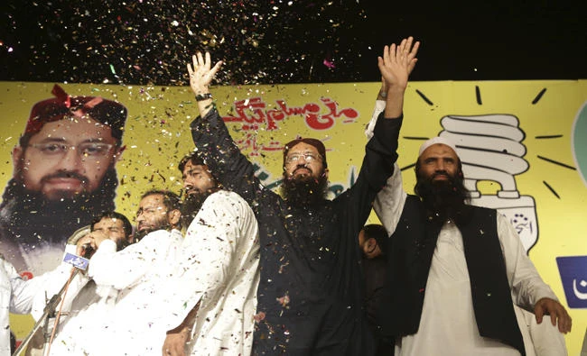 In this Sept. 14, 2017 file photo, Sheikh Yaqub, center, candidate of the newly formed Milli Muslim League party, waves to his supporters at an election rally in Lahore, Pakistan. Pakistan's interior ministry has asked the country's elections overseeing body to ban from politics the new party backed by Islamist Hafiz Saeed, who carries a $10 million US bounty on his head for alleged involvement in 2008 terror attacks in India. (AP Photo/K.M. Chaudary,file)