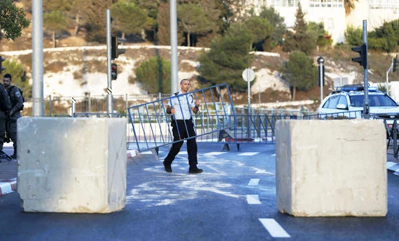 An Israeli policeman carries a metal railing as security forces block a road linking the Arab east Jerusalem neighbourhood of Beit Hanina and West Jerusalem. (AFP)