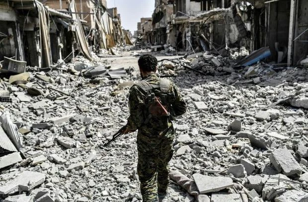 A member of the Syrian Democratic Forces sprints through the rubble on the eastern frontline of Raqa on September 25, 2017. (AFP)