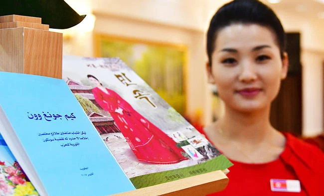 A photo taken on September 21, 2017 shows a waitress posing by a book titled in Arabic "Kim Jong-un", at the Pyongyang Okryu-gwan, a North Korean restaurant in Dubai. (AFP)