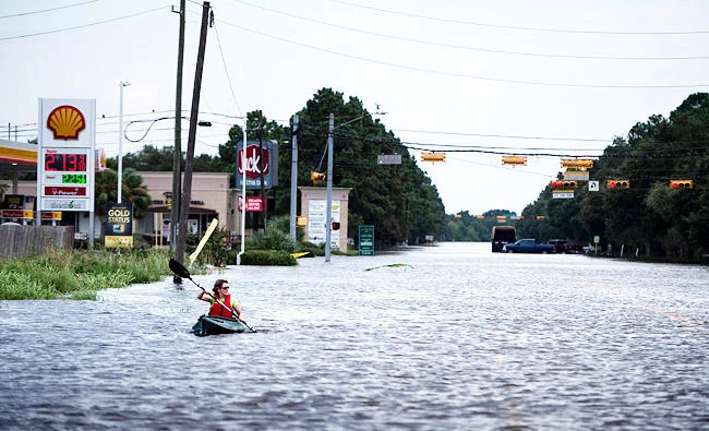 A woman paddles down a flooded road while shuttling deliveries for her neighbors during the aftermath of Hurricane Harvey on August 30, 2017 in Houston, Texas. (AFP)