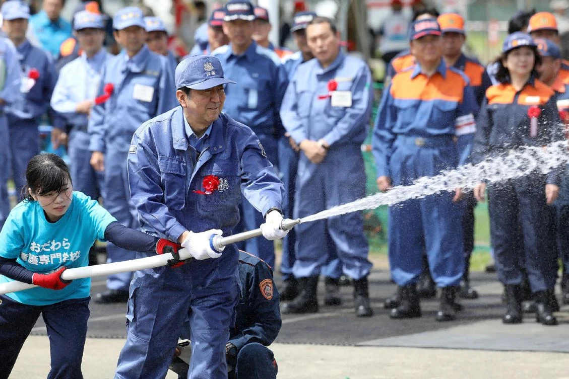 Japan’s Prime Minister Shinzo Abe, right, sprays water during a disaster drill in Odawara, on September 1, 2017. (AFP)